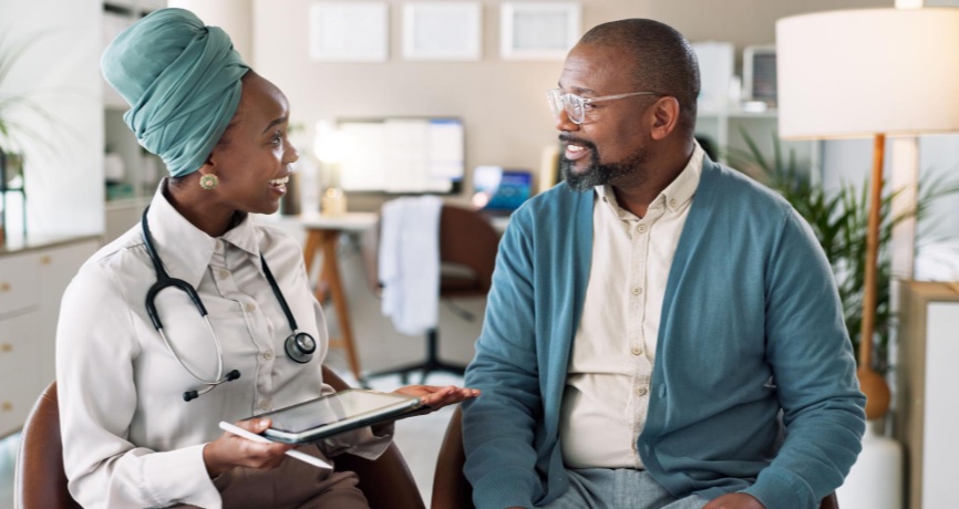 Une médecin échange avec un patient en consultation, tablette en main