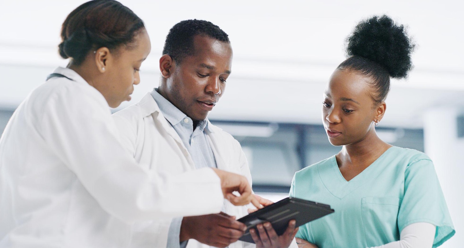 Une médecin, un médecin et une infirmière consultent ensemble un dossier patient sur une tablette